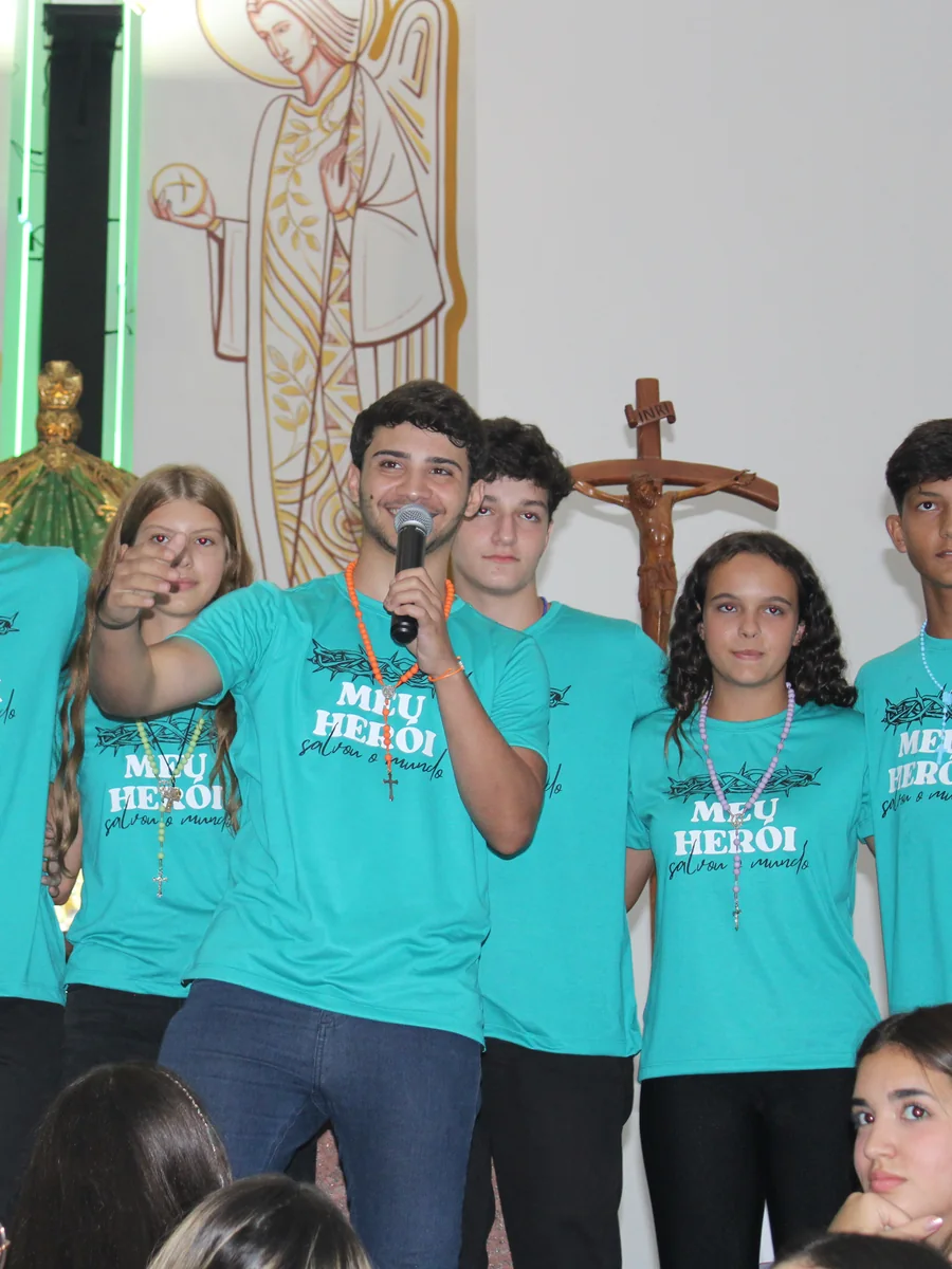 Bruno, fundador da Uniclass, ao microfone num acampamento, cercado de jovens com camisetas feitas pela marca